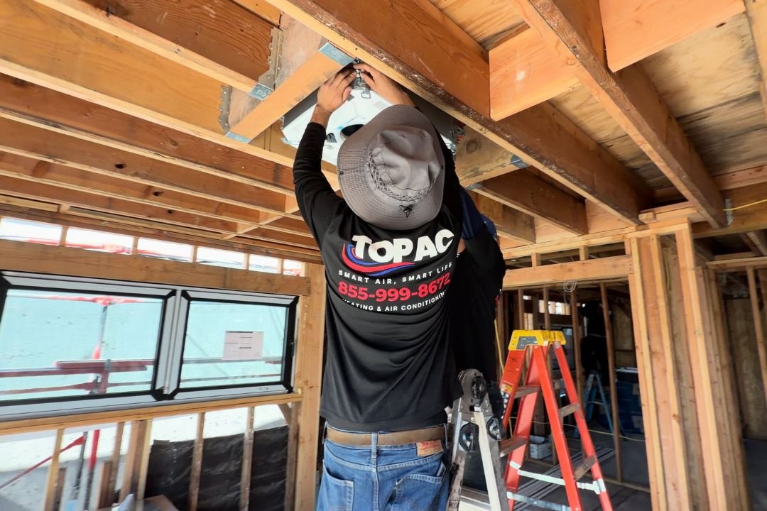 TOP AC technician servicing a commercial rooftop HVAC unit